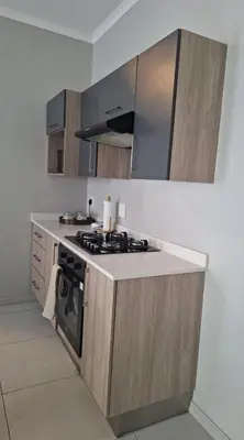 a kitchen with wooden cabinets and a stove top oven at The Convenient Space in Midrand
