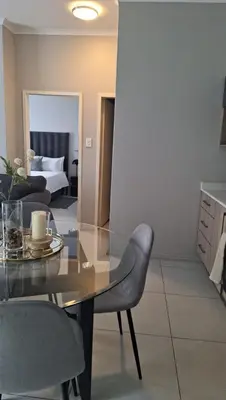 a dining room with a glass table and chairs at The Convenient Space in Midrand