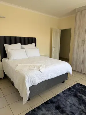 a bedroom with a large bed with white sheets at Your easy stay OR Tambo in Kempton Park
