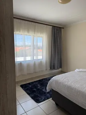 a bedroom with a bed and a large window at Your easy stay OR Tambo in Kempton Park