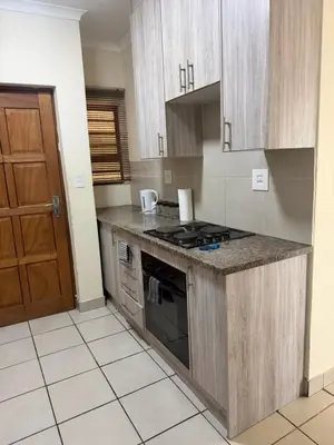 a kitchen with wooden cabinets and a stove top oven at Your easy stay OR Tambo in Kempton Park