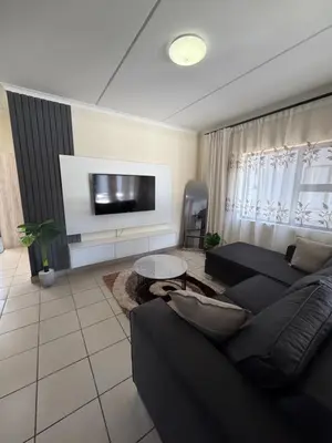 a living room with a black couch and a tv at Your easy stay OR Tambo in Kempton Park