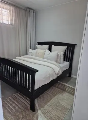a black bed with white pillows in a bedroom at Village Vista at Atlasville 10km from OR Tambo in Boksburg