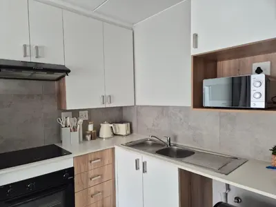 a kitchen with white cabinets and a sink and a microwave at Village Vista at Atlasville 10km from OR Tambo in Boksburg