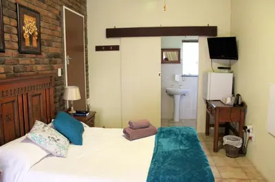 a bedroom with a bed and a desk and a sink at Steendal Guest House in Polokwane