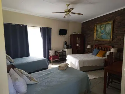 a bedroom with two beds and a ceiling fan at Steendal Guest House in Polokwane