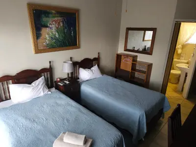 a hotel room with two beds and a mirror at Steendal Guest House in Polokwane