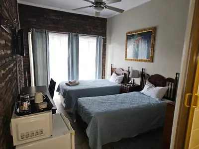 a hotel room with two beds and a window at Steendal Guest House in Polokwane