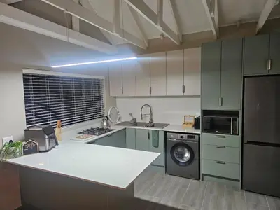 a kitchen with green cabinets and a washing machine at Plekkie Sonder Die See in Centurion