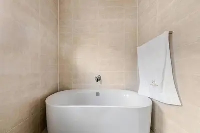 a white tub in a bathroom with a towel on the wall at 2 Bedroom 2 Bathroom Executive Suite in Midrand