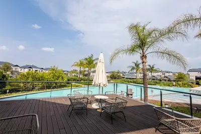 a patio with a table and chairs next to a pool at 2 Bedroom 2 Bathroom Executive Suite in Midrand