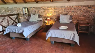 a bedroom with two beds and a brick wall at Umvangazi Rest in Marloth Park