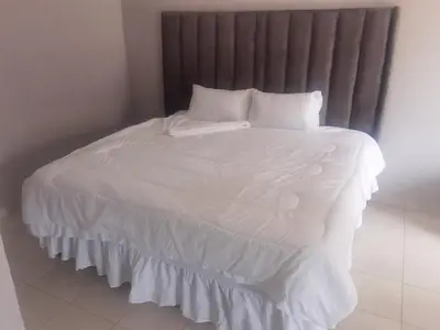 a white bed with white sheets and pillows at Magoveni Accommodation