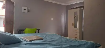 a bedroom with a bed and a green chair at Magoveni Accommodation