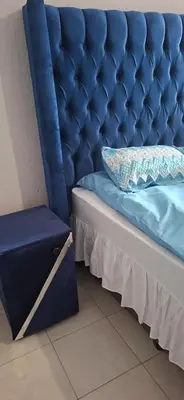 a blue bed with a blue tufted headboard and a blue drawer at Magoveni Accommodation