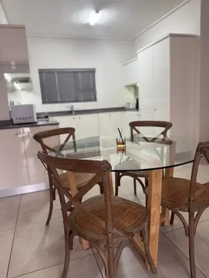 a dining room with a glass table and chairs at AAAA Property Management in Midrand