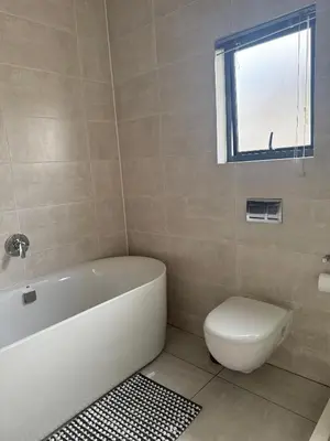 a bathroom with a tub and a toilet and a window at AAAA Property Management in Midrand