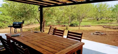 a wooden table and chairs on a porch with a grill at Phumula Bushvilla in Phalaborwa