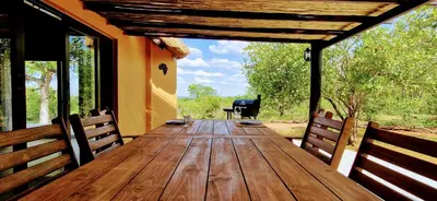 a wooden table on the porch of a house at Phumula Bushvilla in Phalaborwa