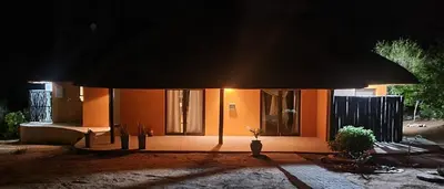 a small house with an umbrella at night at Phumula Bushvilla in Phalaborwa