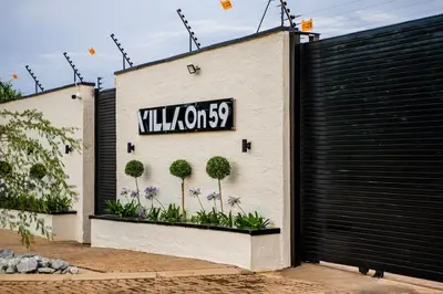 a sign on the side of a building with plants at Villa On 59 in Giyani