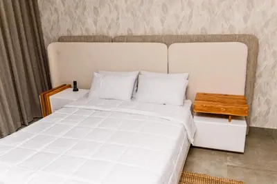 a bedroom with a large white bed with a wooden table at Villa On 59 in Giyani