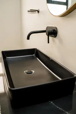 a black sink with a faucet and a mirror at Villa On 59 in Giyani