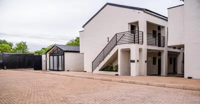 a white house with a staircase on the side of it at Villa On 59 in Giyani