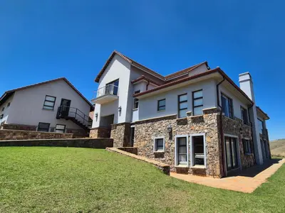 a large white house on a grassy field at Highlands Retreat Loft Unit in Highland Gate Golf and Trout 1135 in Dullstroom