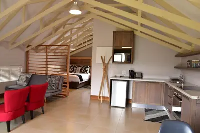 a kitchen with red chairs and a room with a bed at Highlands Retreat Loft Unit in Highland Gate Golf and Trout 1135 in Dullstroom