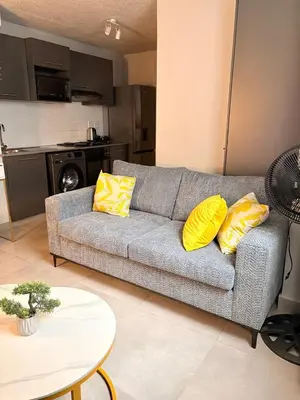 a living room with a couch with two yellow pillows at Unit 87 at Circa Lynwood in Pretoria