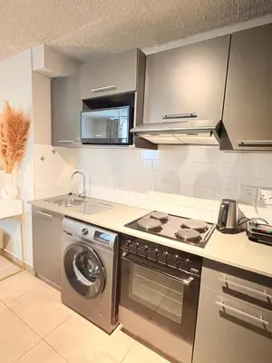 a kitchen with a stove and a washing machine at Unit 87 at Circa Lynwood in Pretoria