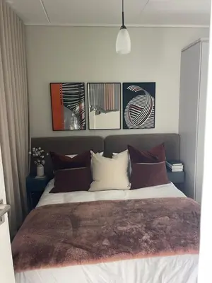 a bedroom with a bed with four pictures on the wall at The Blyde Luxury Apartment in Pretoria