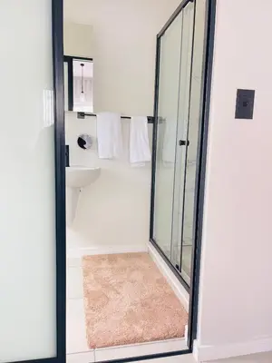 a bathroom with a glass shower with a rug at The Blyde Luxury Apartment in Pretoria