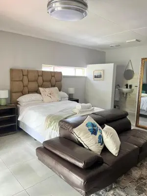 a bedroom with a large bed and a leather couch at 14 Isabel in Centurion