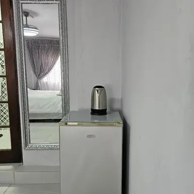 a small refrigerator in a room with a mirror at 14 Isabel in Centurion