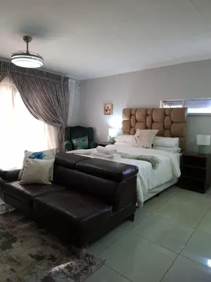 a bedroom with a large bed and a leather couch at 14 Isabel in Centurion