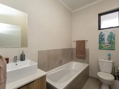 a bathroom with a tub and a toilet and a sink at Woodland Haven in Midrand