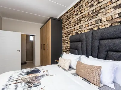a bedroom with a brick wall and a bed at Woodland Haven in Midrand