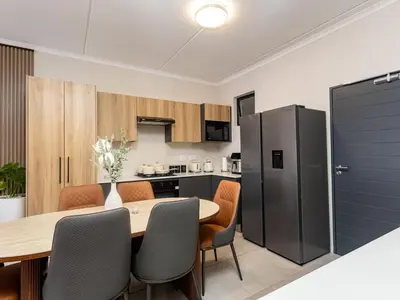 a kitchen and dining room with a table and chairs at Woodland Haven in Midrand