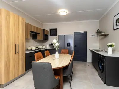 a kitchen and dining room with a wooden table and chairs at Woodland Haven in Midrand