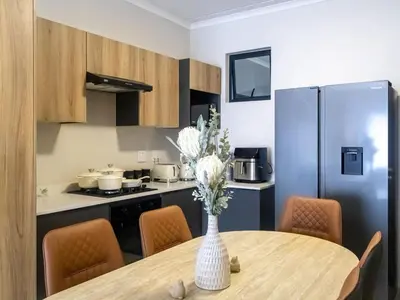 a kitchen and dining room with a table and a refrigerator at Woodland Haven in Midrand