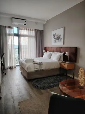 a bedroom with a large bed and a table at Menlyn Maine Trilogy Apartment 1220 & 1221 in Pretoria