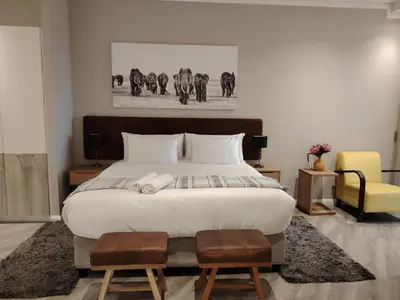 a bedroom with a large white bed and a yellow chair at Menlyn Maine Trilogy Apartment 1220 & 1221 in Pretoria