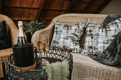 a bottle of champagne on a wicker chair with a pillow at WildlifeEstateVilla-Pool-Boma-Bushlife in Hoedspruit