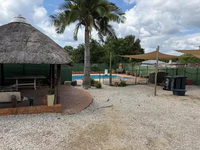 a hut with a palm tree and a swimming pool at Entire Premises ideal for large groups and reunions in Pretoria