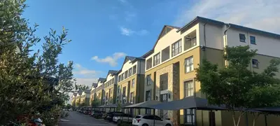 a yellow building with cars parked on a street at Waterfall Midrand in Northdene