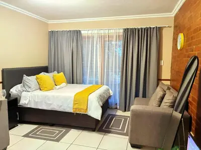 a bedroom with a bed and a chair and a window at Apartment of Convenience-In the heart of Midrand in Midrand