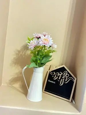 a white vase filled with pink flowers next to a box at Apartment of Convenience-In the heart of Midrand in Midrand