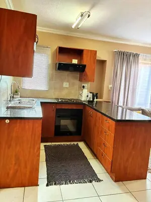 a kitchen with wooden cabinets and a black counter top at Apartment of Convenience-In the heart of Midrand in Midrand